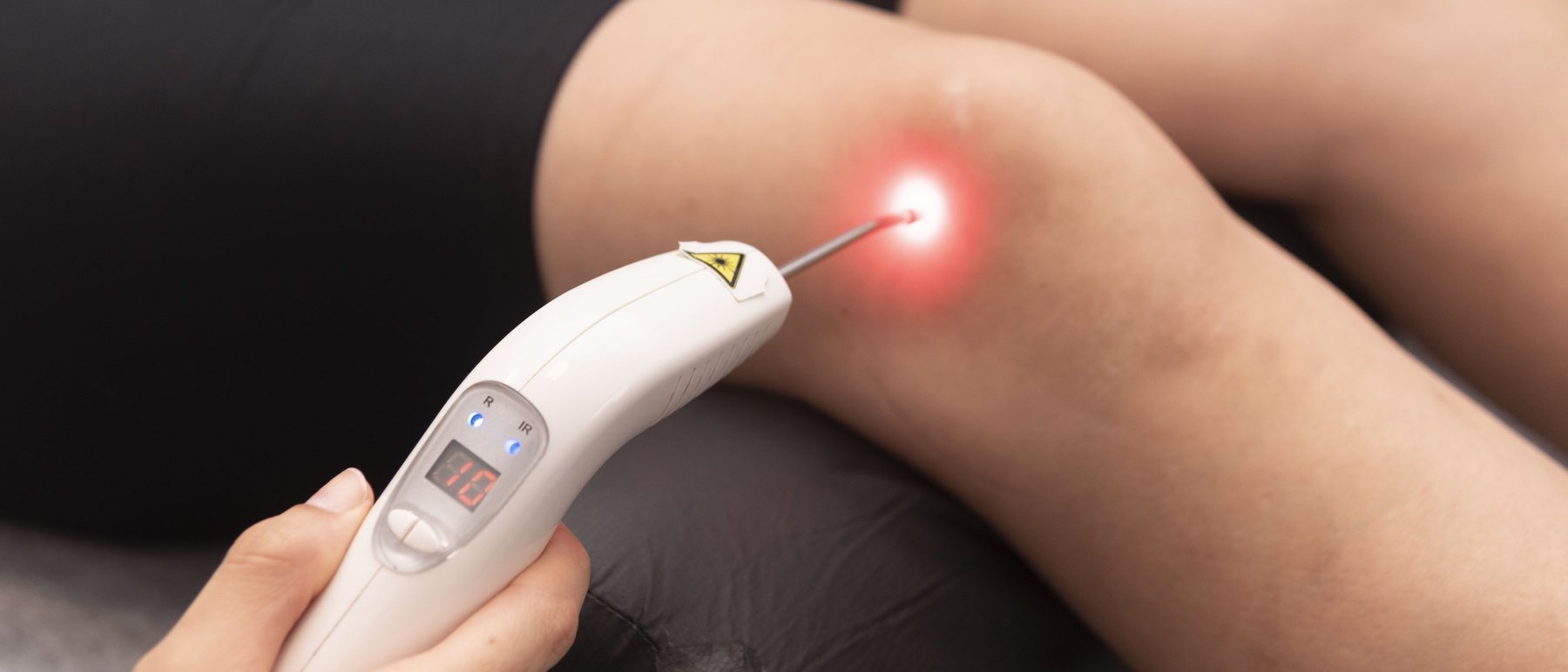Aplicação de laser terapêutico no joelho durante sessão de fisioterapia