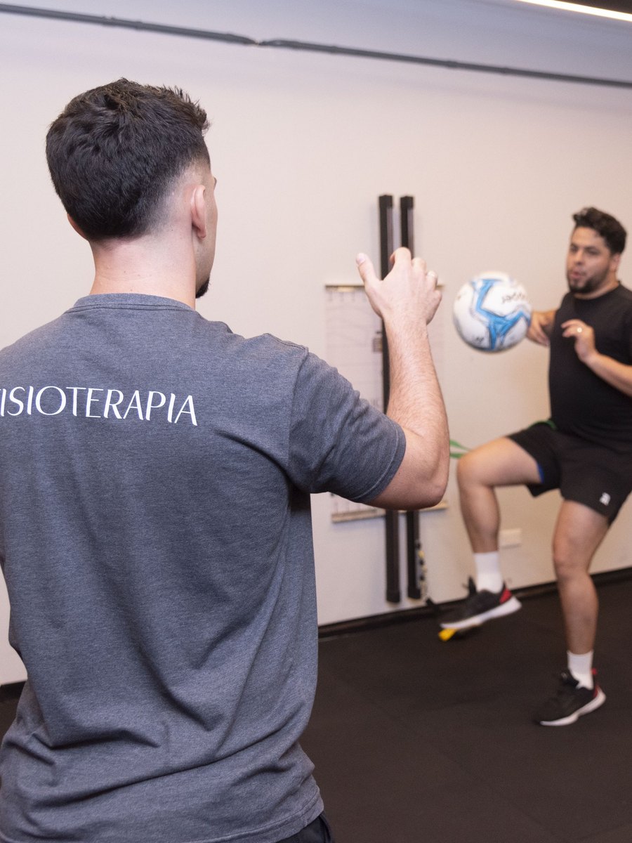 Fisioterapeuta conduzindo exercício de retorno ao esporte com bola, na sala de reabilitação