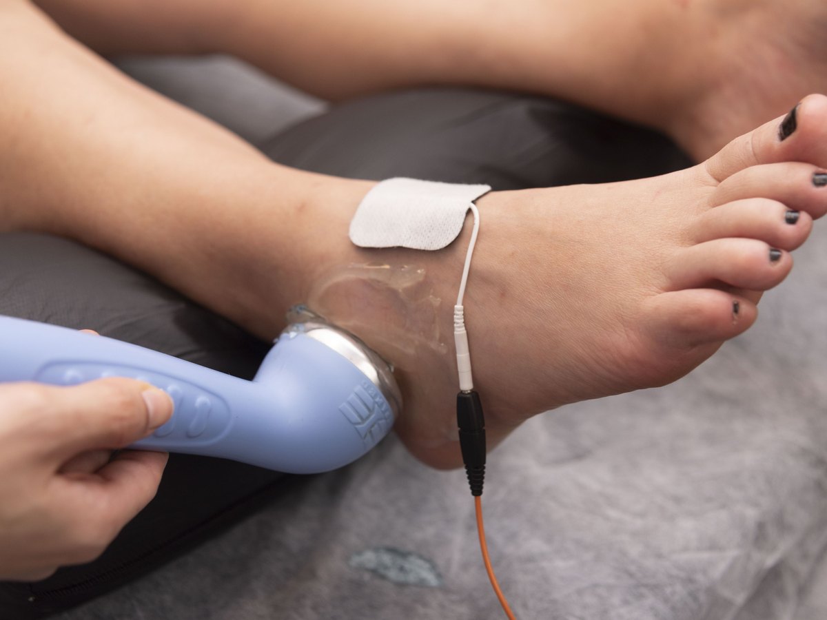 Aplicação de recurso terapêutico no tornozelo durante sessão de fisioterapia